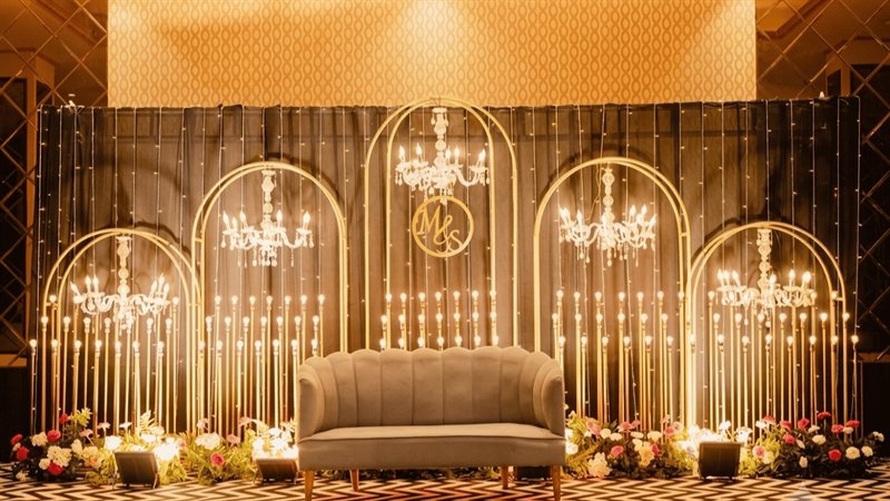 Gold arch reception stage with crystal chandeliers and candle-light uprights in Jaipur by Shava Moments