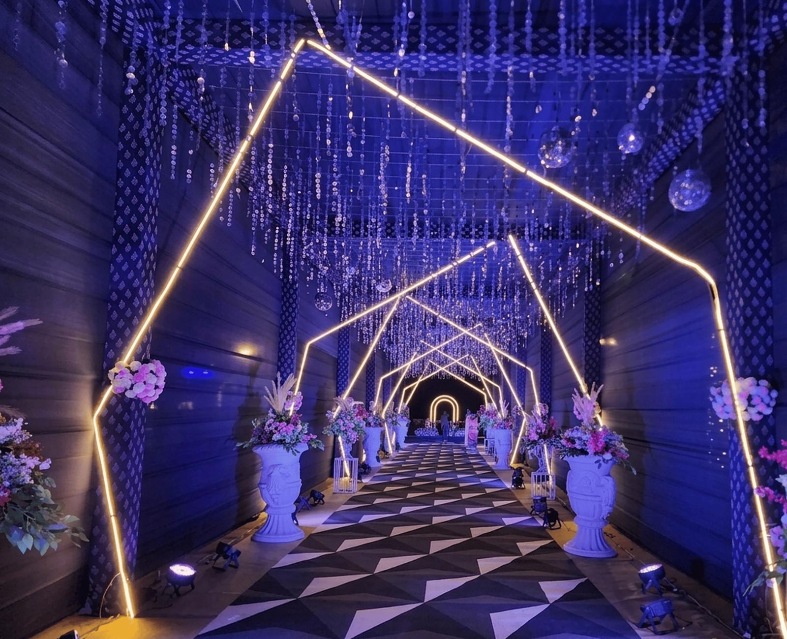 Lit geometric entrance walkway with hanging crystals and floral urns for a sangeet in Jaipur by Shava Moments