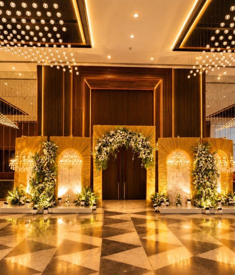 Gold panelled entrance with chandelier arches and white floral clusters for a wedding in Jaipur by Shava Moments